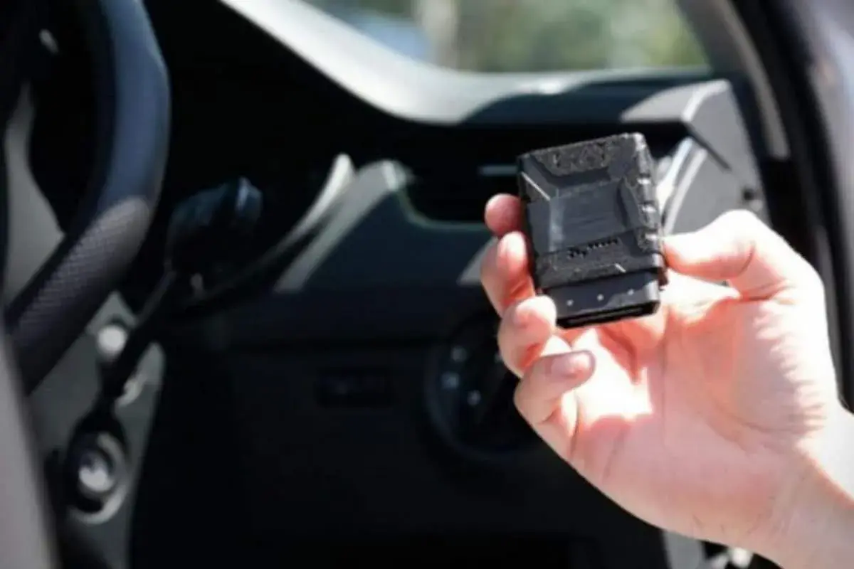 Una mano tiene una scatola nera macchina, un dispositivo tecnologico per monitorare le prestazioni del veicolo.