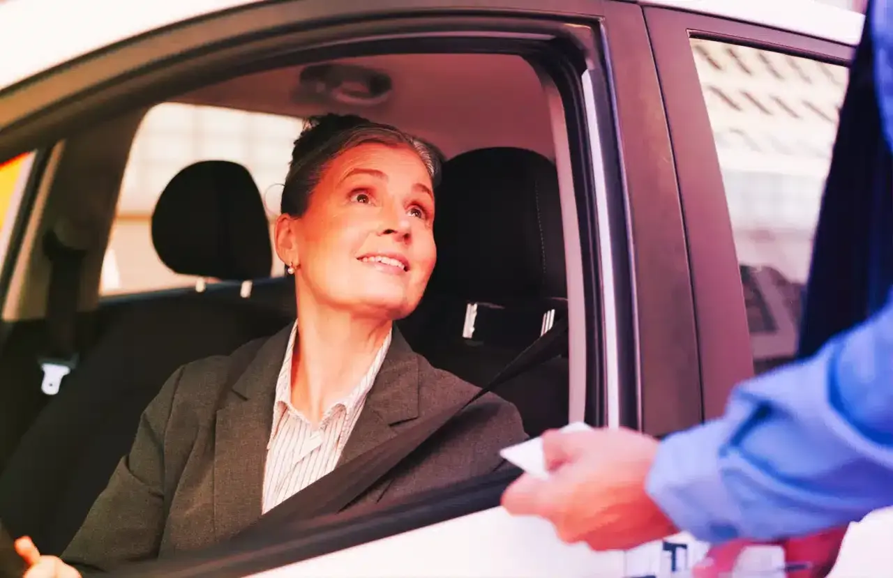 Donna in auto riceve un documento, forse per l'assicurazione dopo scadenza.
