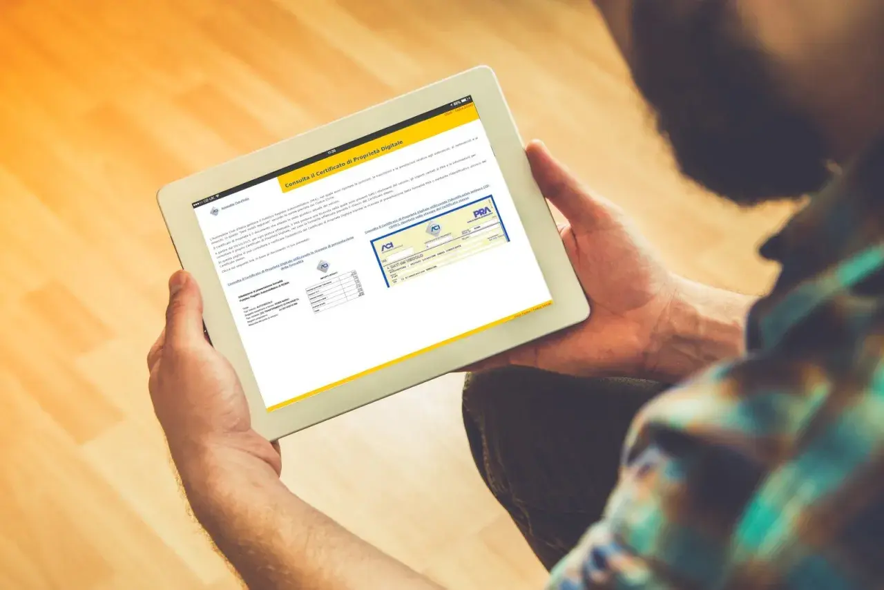 Uomo consulta su tablet il certificato di proprietà digitale, un documento essenziale per la gestione dei veicoli.