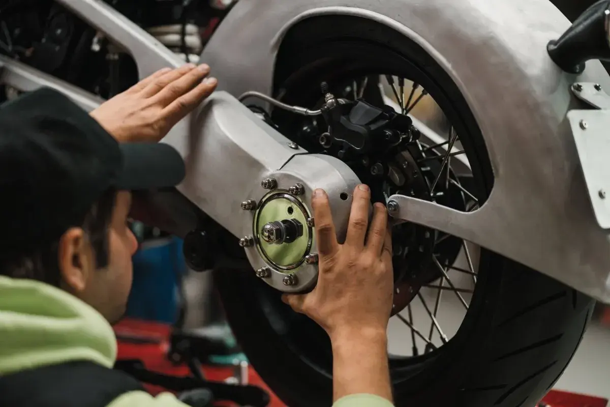 Meccanico effettua il primo tagliando moto, controllando il mozzo posteriore e il freno.
