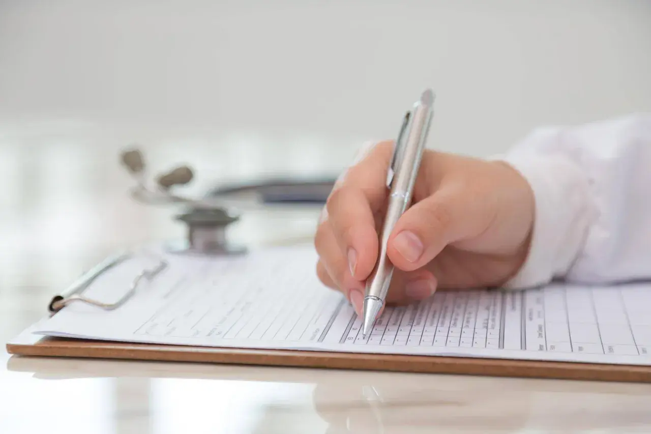 Medico compila modulo per la validità certificato medico patente b. Stetoscopio sullo sfondo.