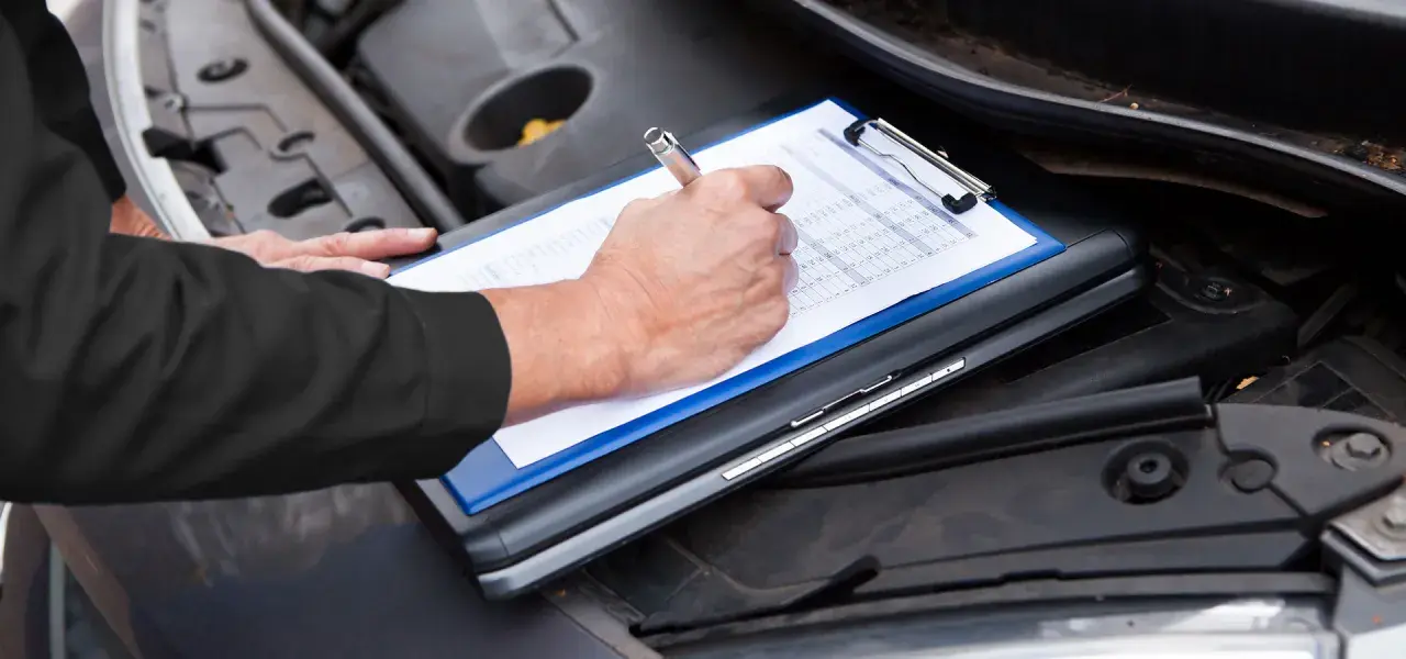 Un meccanico controlla il libretto per sapere tagliando auto ogni quanto va fatto.