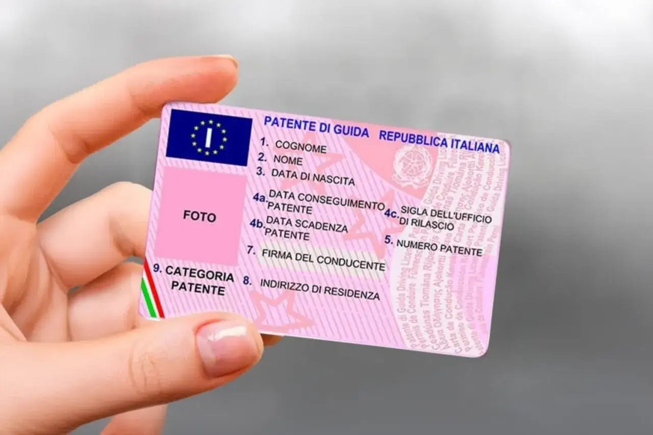 Mano che mostra una patente di guida italiana, documento essenziale per la classe patente.