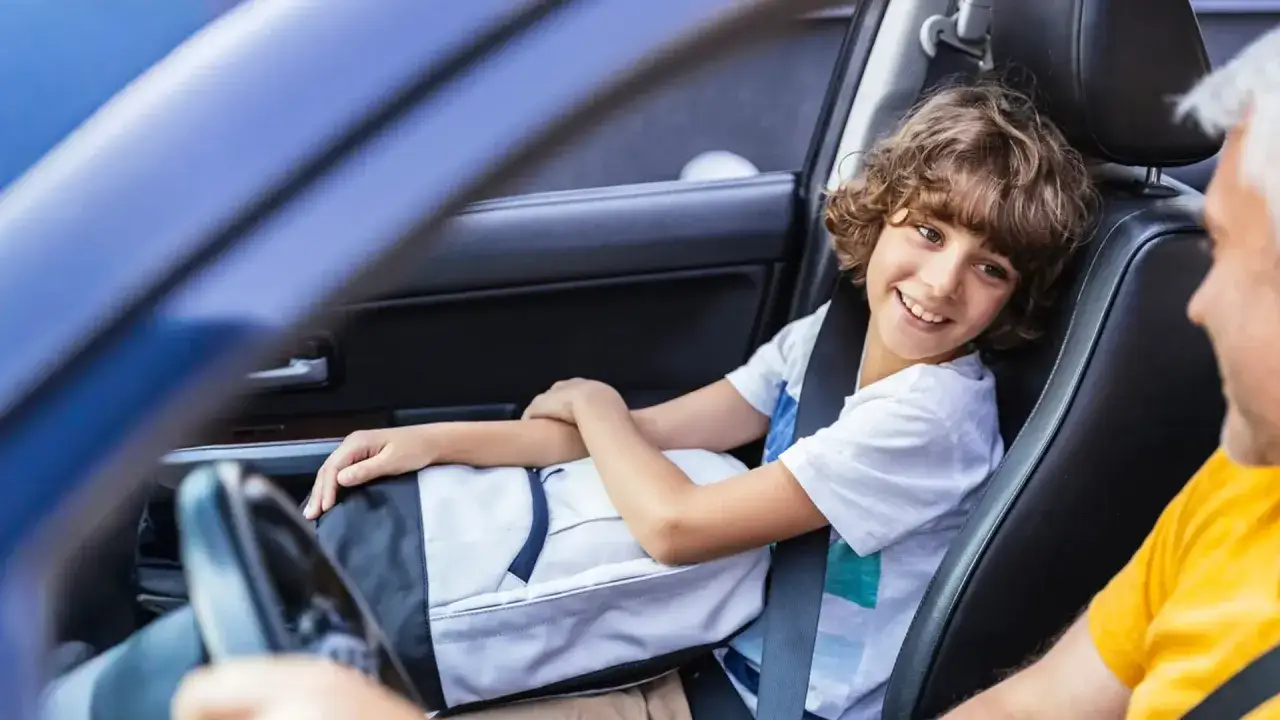 Un bambino sorridente in auto, con la cintura allacciata, ricorda che esiste ancora la legge Bersani per la sicurezza.