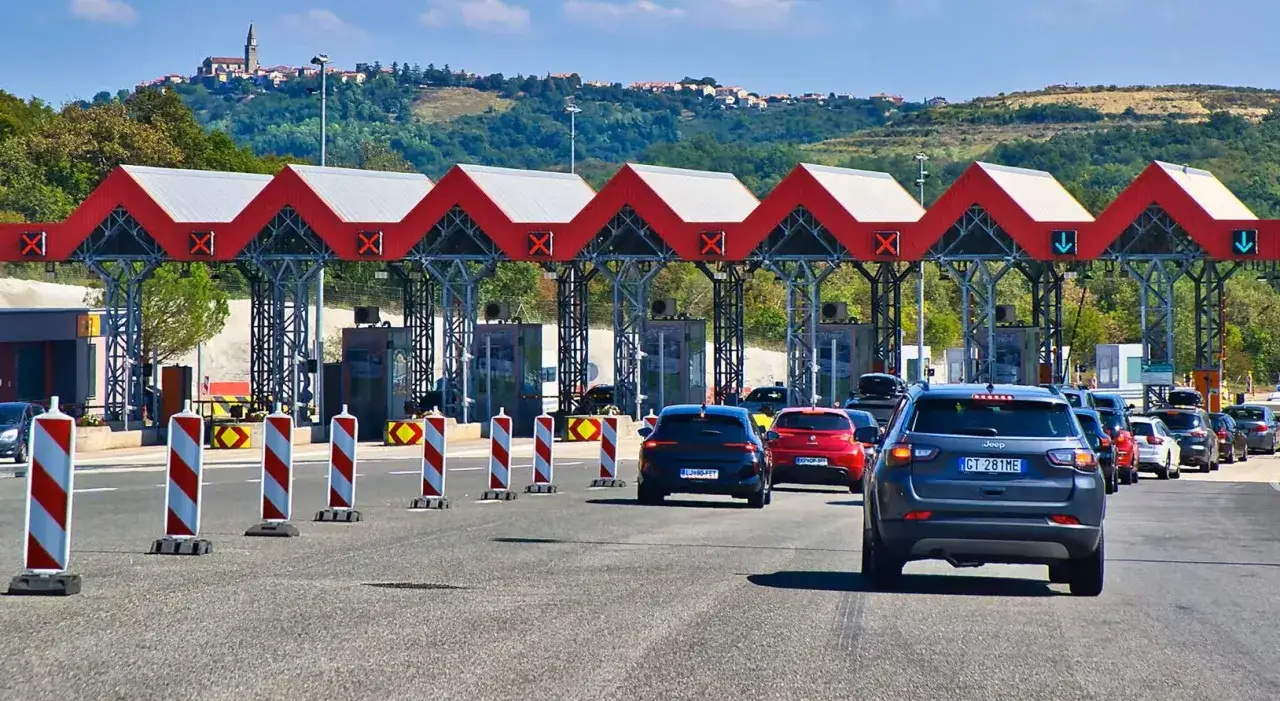 Coda di auto in attesa al casello delle autostrade croate. Il pedaggio è visibile sotto le tettoie rosse.