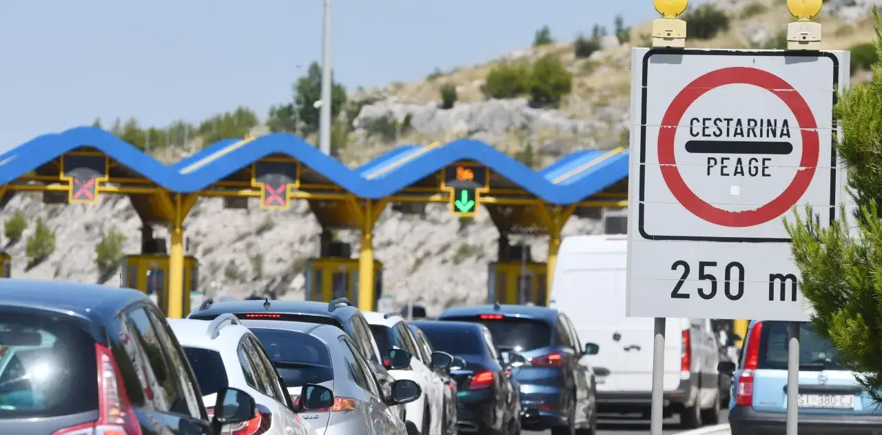 Coda di auto in attesa al casello autostradale croato. Il cartello indica