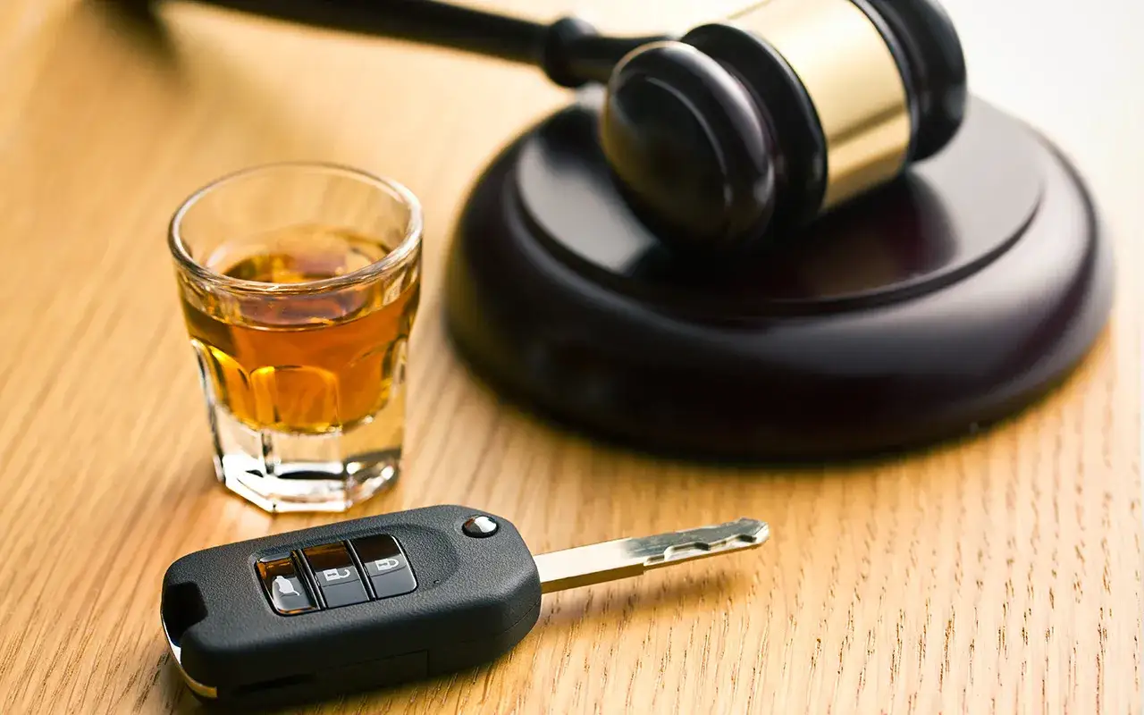 Chiavi auto, bicchierino di whisky e martelletto del giudice: simbolo di un ricorso vinto per revoca patente.