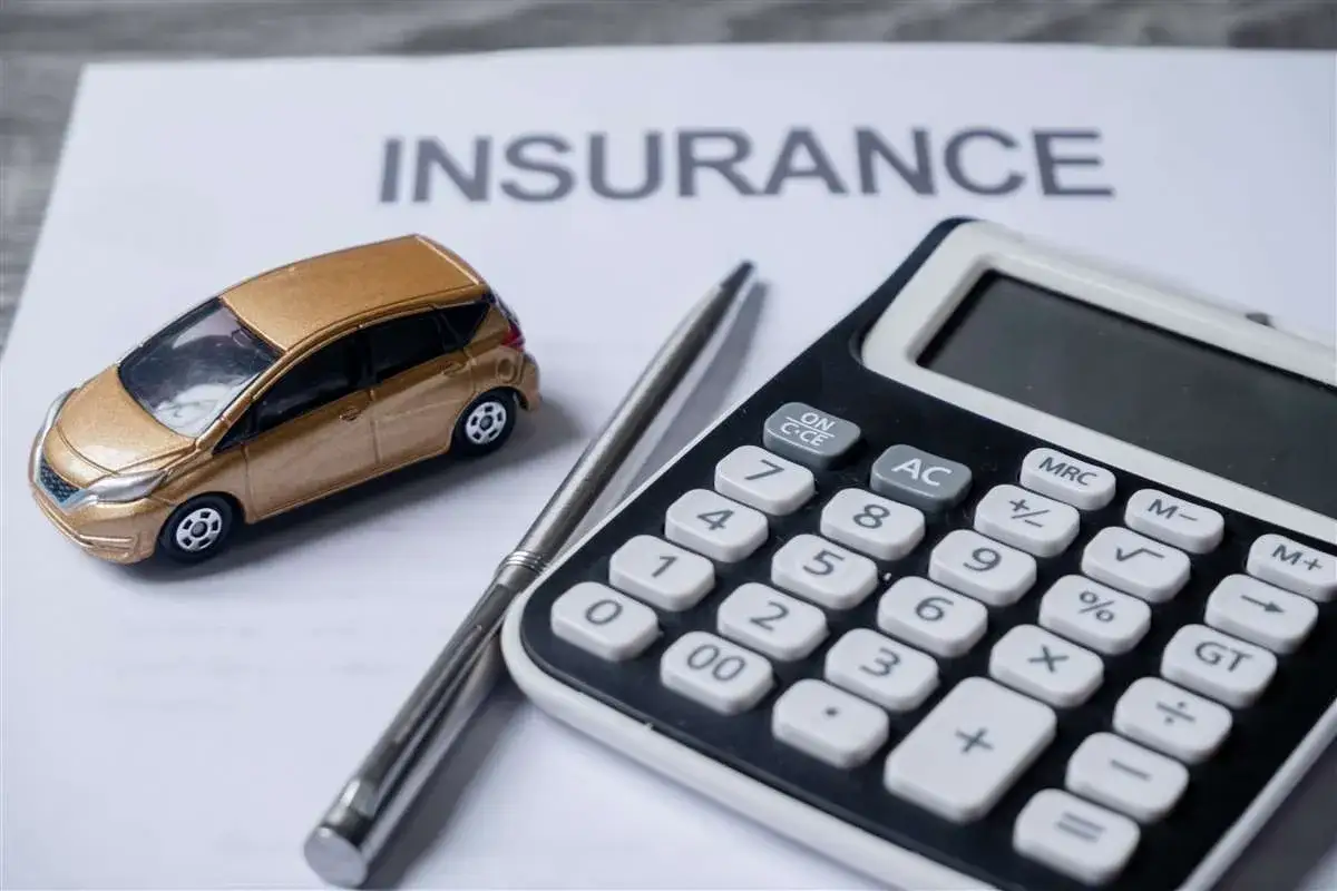 Modellino auto dorata, calcolatrice e penna su foglio con scritta